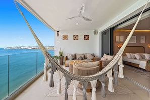 A balcony with a hammock, a sofa, and a dining area with a view of the sea. - Beachfront Lux 3BR, 2 Pools + Rooftop | Panarea 7B (Bucerías)