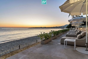 A beachfront seating area with planters, a poolside lounge, and umbrellas. - Beachfront Lux 3BR, 2 Pools + Rooftop | Panarea 7B (Bucerías)