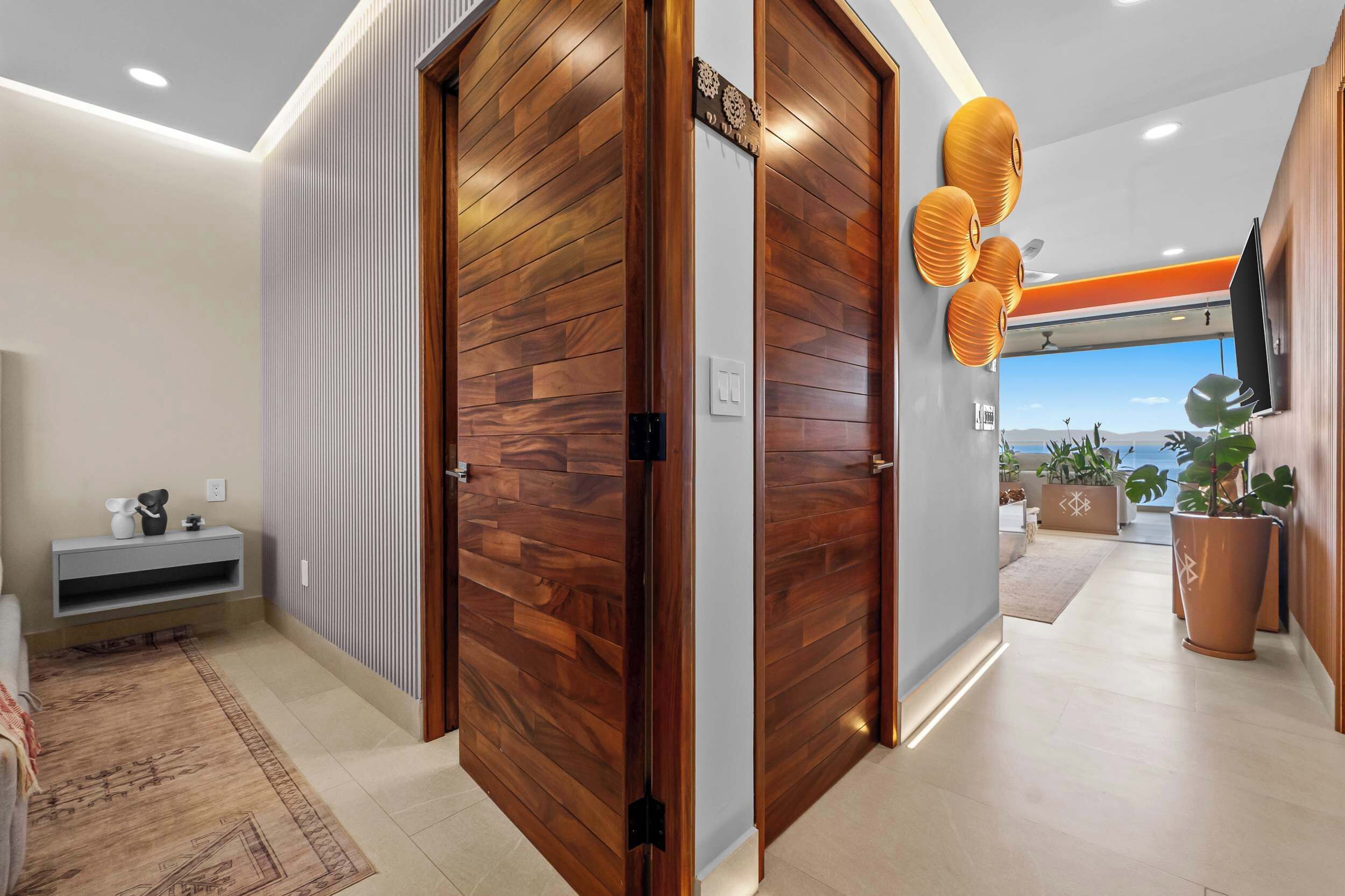 Ein modernes Interieur mit einer Holztür, einer grauen Konsole, Blick durch eine Glastür und einem Blumentopf.