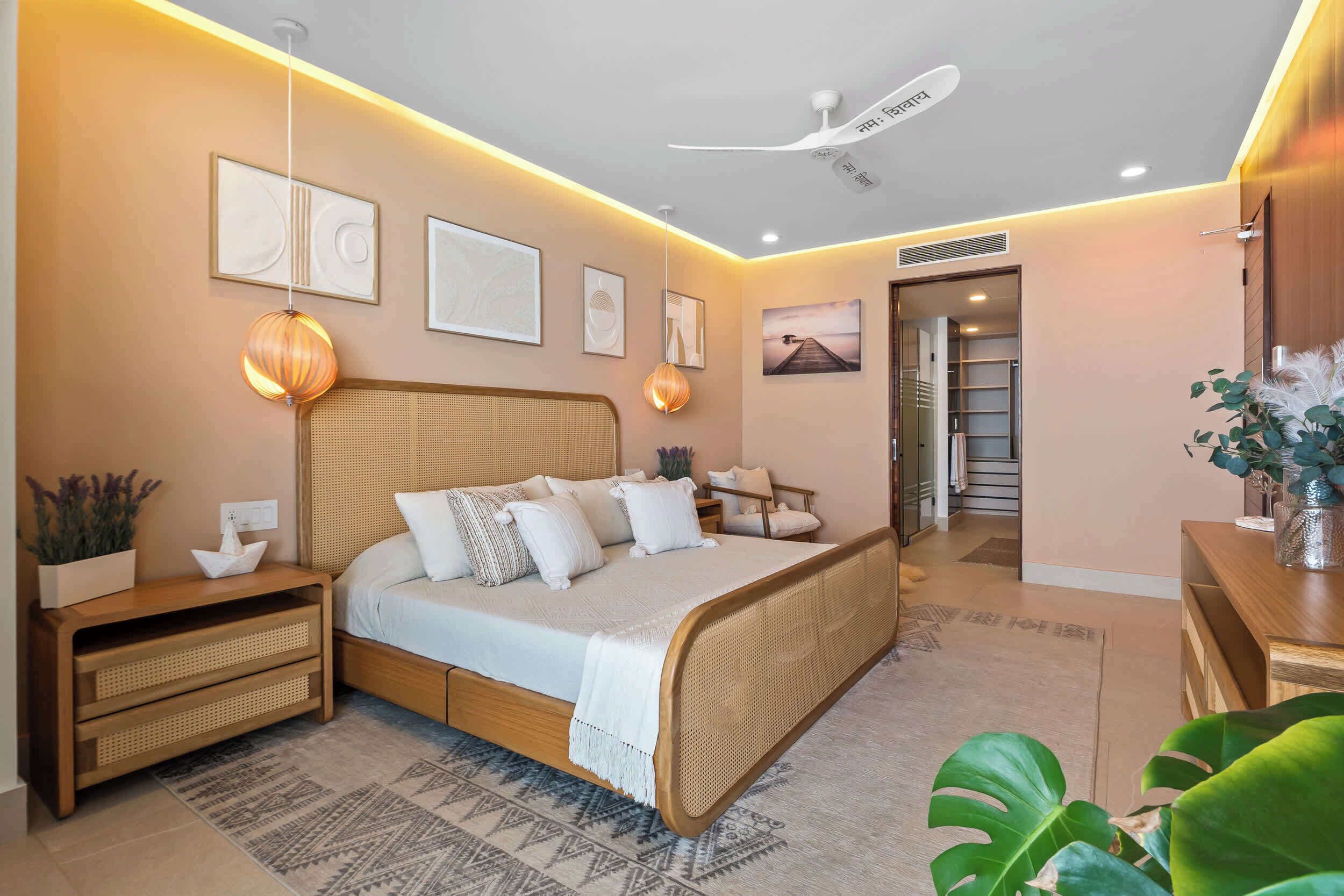 A bedroom with a bed, bedside tables, a ceiling fan, wall art, and a staircase leading to another room.