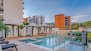 A rooftop pool area with lounge chairs, a glass railing, and a view of surrounding buildings. - Edificio Riomaggiore City Tower (Cali)