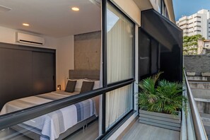 A modern bedroom with a bed, a large window, and a balcony with plants. - Edificio Riomaggiore City Tower (Cali)