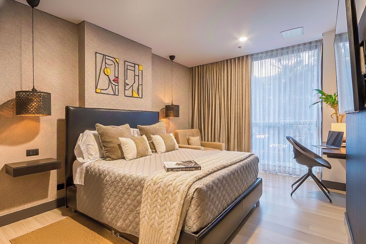 A modern hotel room with a large bed, a desk, and a view of the city.