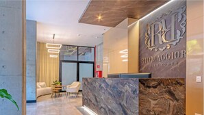 A reception area with a marble reception desk, a seating area with a sofa and chairs, and a large window. - Edificio Riomaggiore City Tower (Cali)
