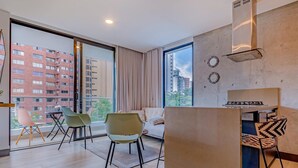 A modern apartment with a large balcony, a sofa, two chairs, and a kitchen area. - Edificio Riomaggiore City Tower (Cali)