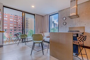 A modern apartment with a large balcony, a sofa, two chairs, and a kitchen area. - Edificio Riomaggiore City Tower (Cali)