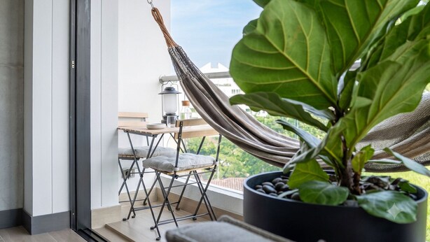 A balcony with a hammock, a potted plant, and a small table with a chair. - Edificio Riomaggiore City Tower (Cali)
