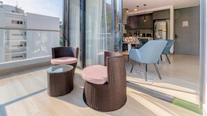 Un balcon moderne avec des meubles en osier, une table en verre et une vue sur le paysage urbain.