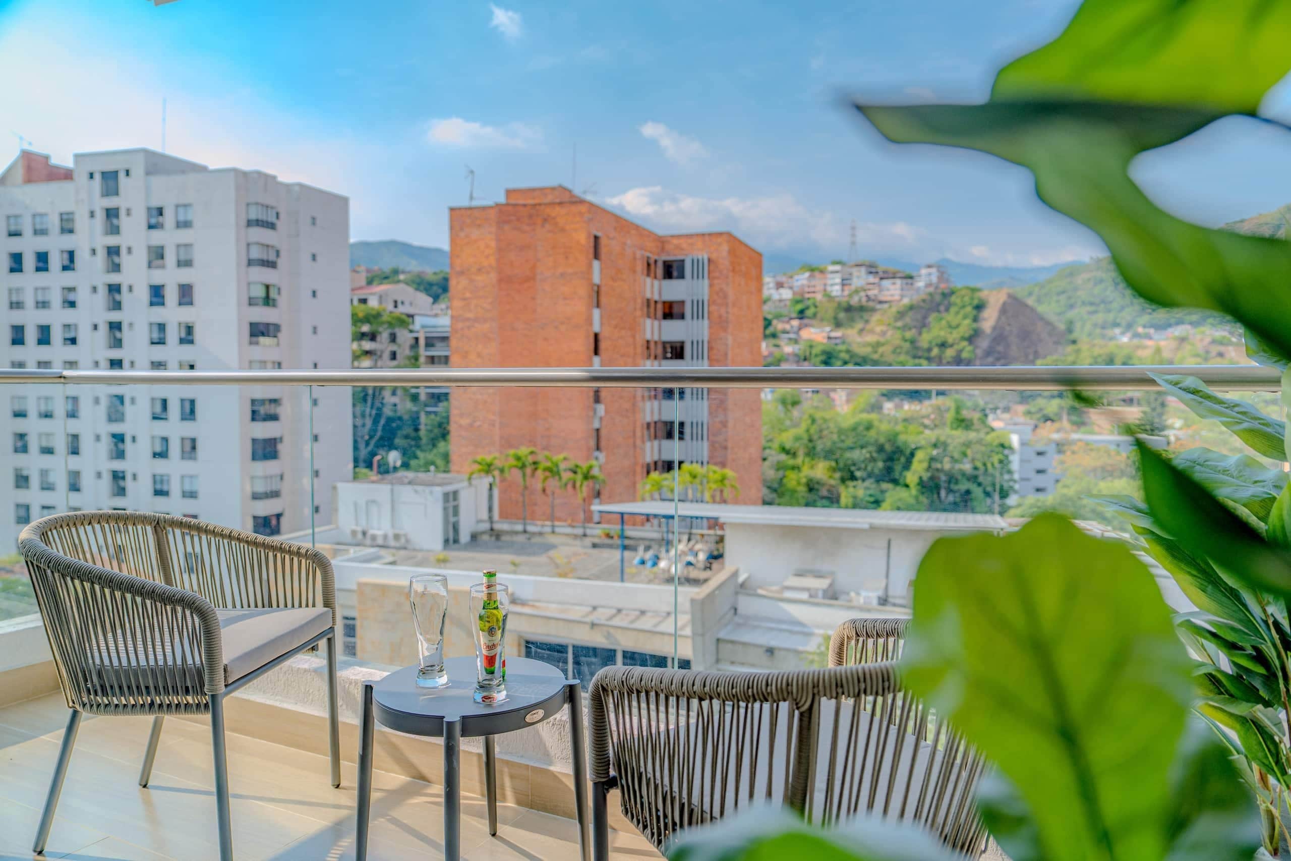 Een balkon met rieten stoelen, een kleine tafel en een fles water.