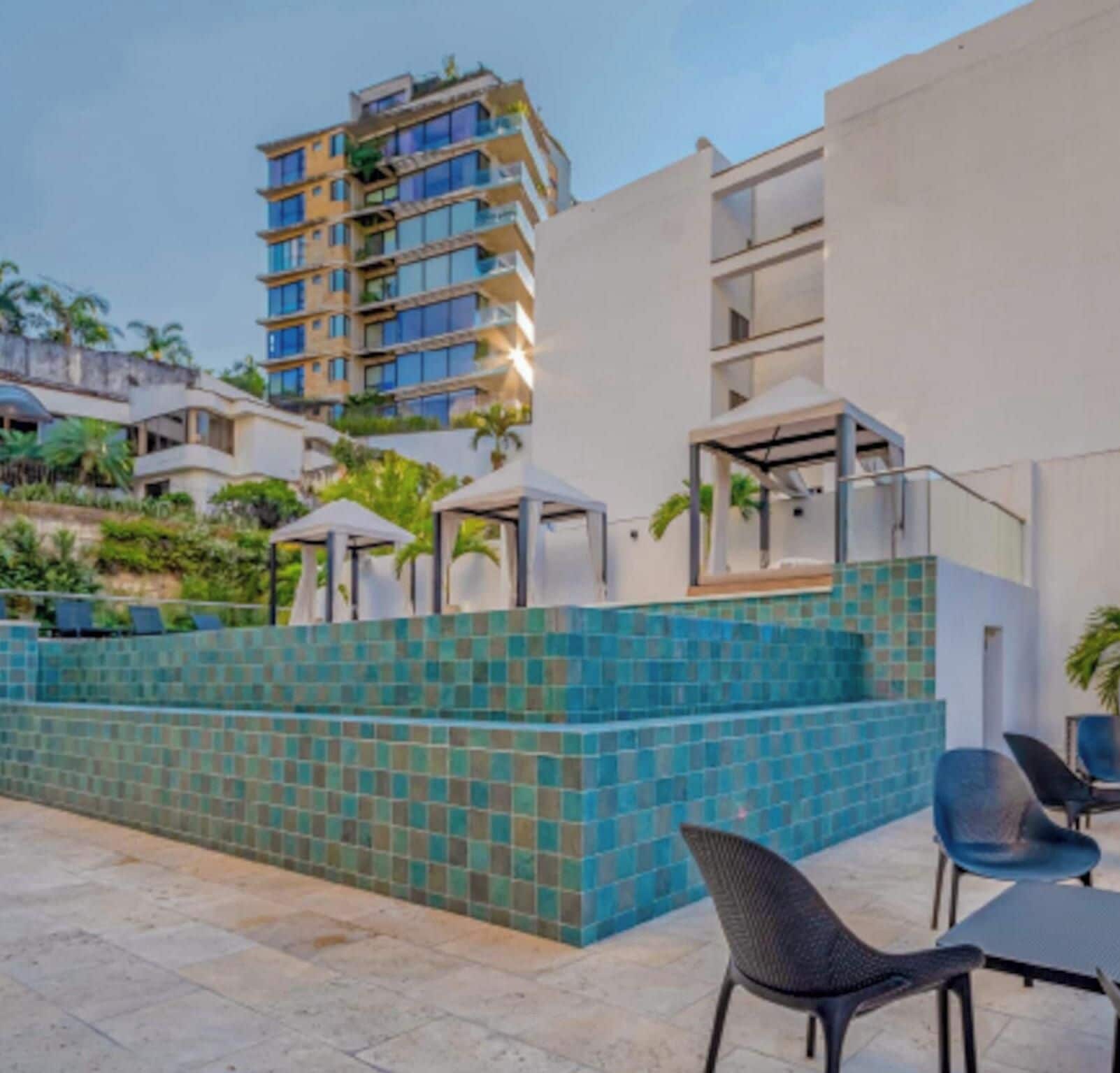 Um edifício moderno com várias varandas, uma parede revestida de azulejos e área de estar ao ar livre.