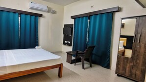 A hotel room with a bed, a desk, a chair, a wardrobe, and a mirror.