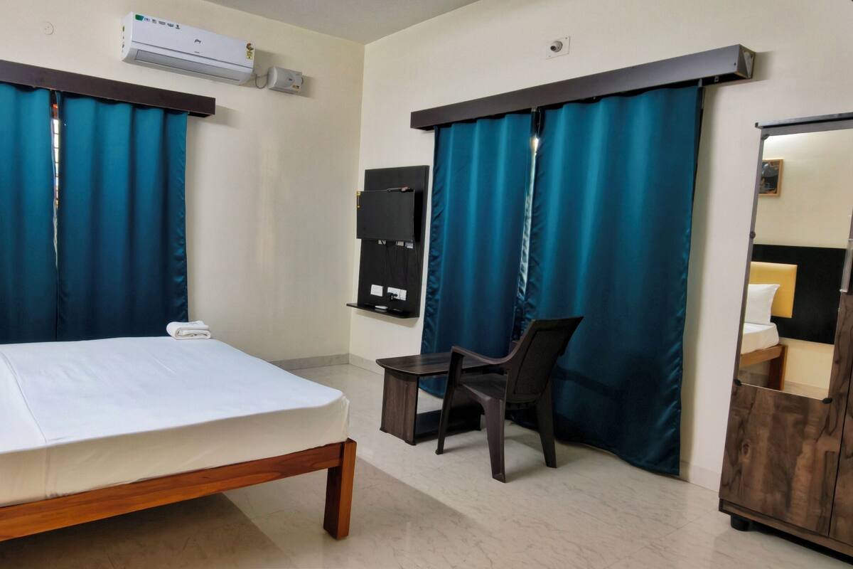 A hotel room with a bed, a desk, a chair, a wardrobe, and a mirror.