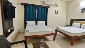 A hotel room with two beds, a desk, a chair, an air conditioner, and a water bottle on the floor.