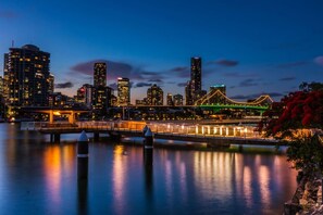 A city skyline at dusk with illuminated buildings and a bridge. - Courtyard 1-Bed Apartment in New Farm (New Farm)