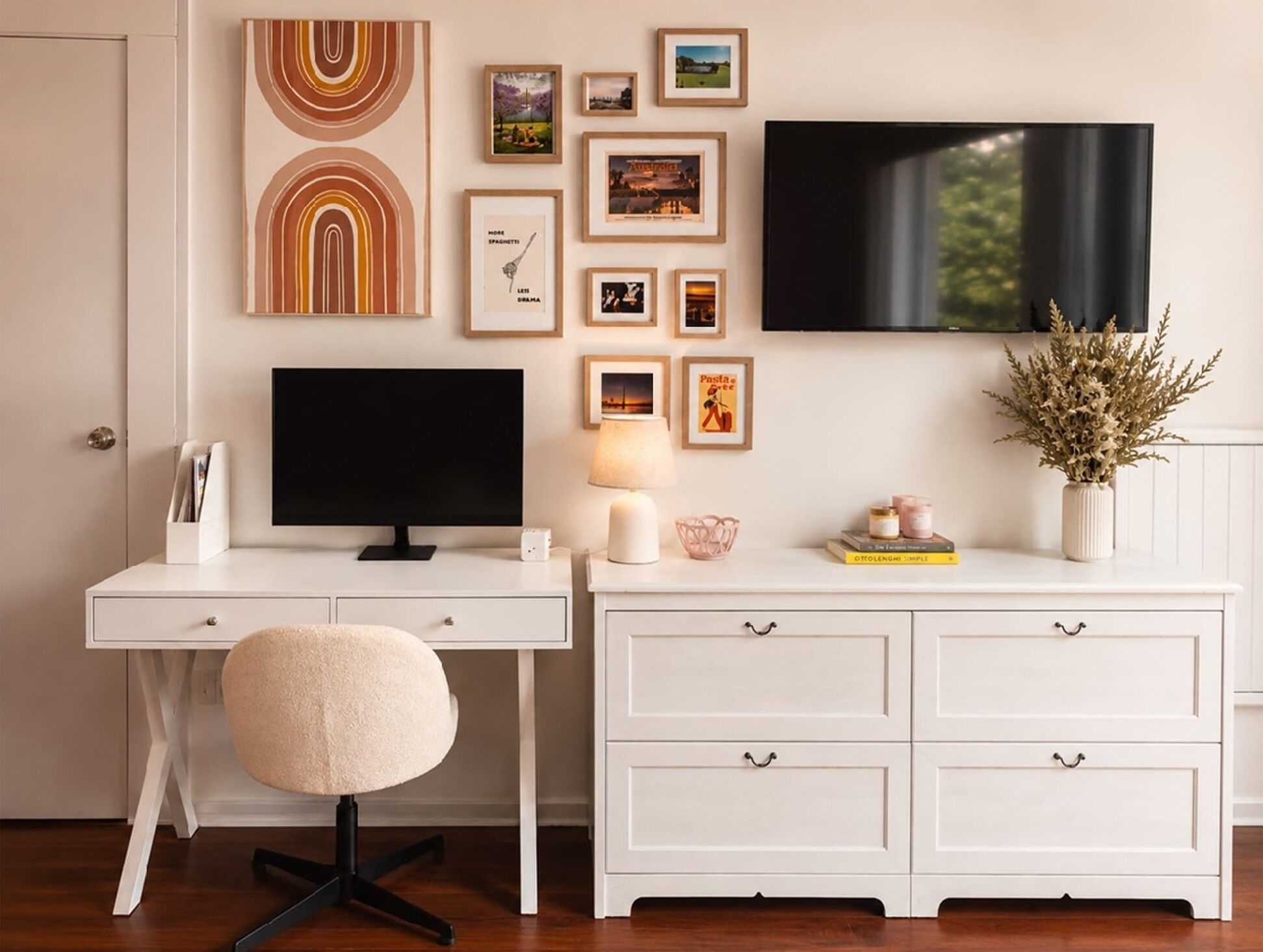 A modern, minimalist room with a white desk, a black monitor, a fluffy chair, and a TV mounted on the wall.
