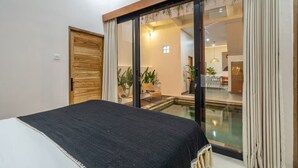 A bedroom with a bed, a sliding glass door leading to a living area, and a small pool. - Kutesa Villa Bali (Kerobokan)