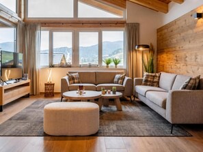 Ein modernes Wohnzimmer mit einer Couch, zwei Beistelltischen, einem Couchtisch und einem Fernseher.
