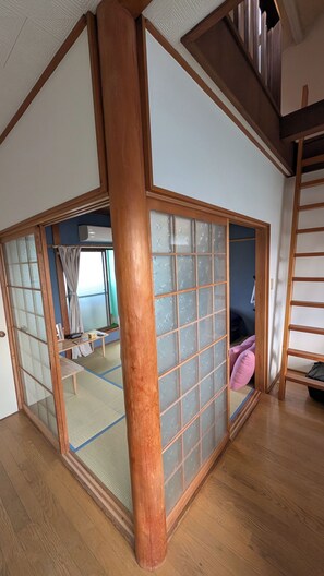 Ein traditioneller japanischer Raum mit Tatami-Boden, einer verschiebbaren Shoji-Schirmwand und einem Holzträger-System.