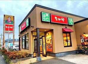 Ein Restaurant mit Schildern in japanischer Schrift, einem Fahrrad vor der Tür und blauem Himmel.