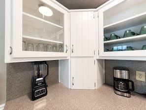 A kitchen with white cabinets, a Ninja blender, a Krups coffee maker, and green dishware on shelves. - THE OWL POST - Pool, Games & Cinema Room (Columbus)