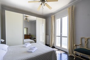 Ein Hotelzimmer mit Bett, einem Sessel, einem großen Spiegel und einem Deckenventilator.