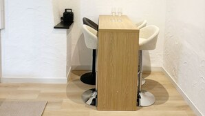 A corner room with a wooden table, two white chairs, a small shelf with a coffee machine, and a framed picture on the wall. - Cozy 1BR & Living Room Near City Center (Ghent)