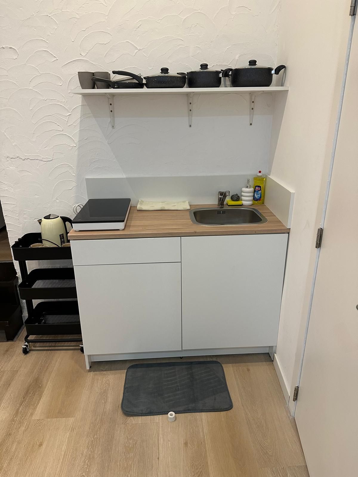 Une cuisine de taille réduite, dotée d’un plan de travail en bois, d’un évier et d’une cuisinière.