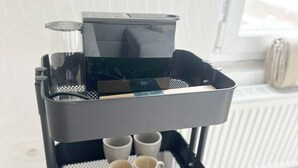 Une machine à café noire, posée sur un chariot, avec quatre tasses et une tasse blanche.