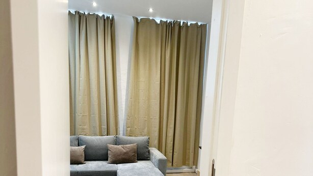 A modern living room with a grey sectional sofa, a small ottoman, and a light-colored rug. - Cozy 1BR & Living Room Near City Center (Ghent)
