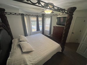 Ein Schlafzimmer mit einem Himmelbett, einem Schminktisch, einem Fernseher und einer Tür.