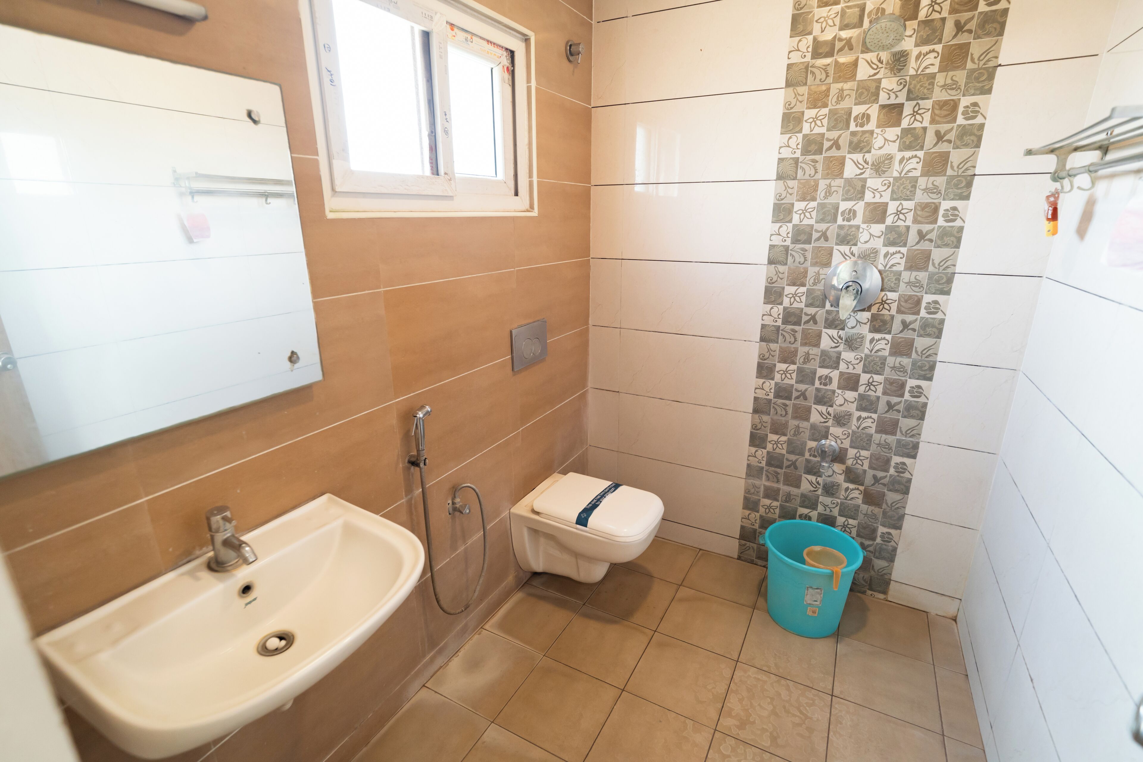 A bathroom with a sink, toilet, shower, and a window.