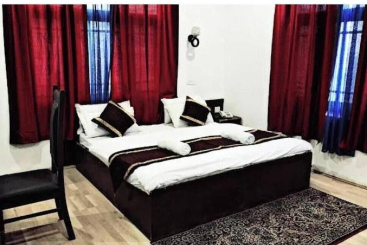 A bedroom with a bed, a chair, a nightstand, and a rug.