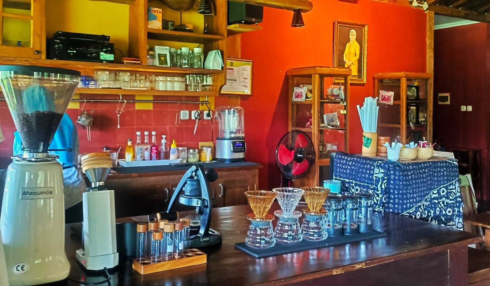 A bar area with a coffee machine, various glass containers, and a fan.