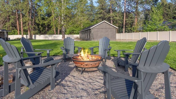 An outdoor seating area with Adirondack chairs and a fire pit. - Family Stay Central To Glacier + Whitefish (Columbia Falls)