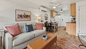 A living room with a sofa, a coffee table, and a dining area with a table and chairs. - Family Stay Central To Glacier + Whitefish (Columbia Falls)