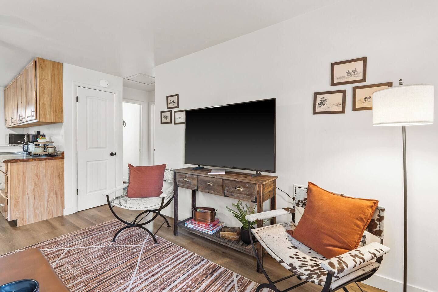 Ein Wohnzimmer mit Fernseher, einer Couch, einem Couchtisch und einer Küchenzeile mit Holzausstattung.