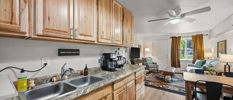 A kitchen with wooden cabinets, a granite countertop, a coffee maker, and a dining area with a table and chairs.