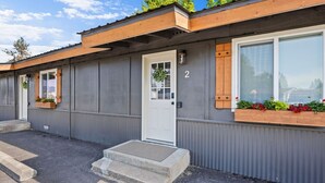 A motel with a grey exterior, numbered rooms, and flower boxes on the windowsills. - Glacier NP Retreat w/ Modern Comforts & Pickleball (Columbia Falls)