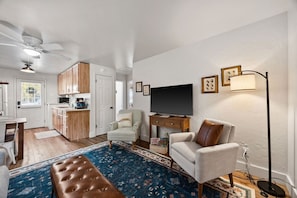 Un espace de vie compact comprenant un coin cuisine, un téléviseur, un canapé et un tapis à motifs.
