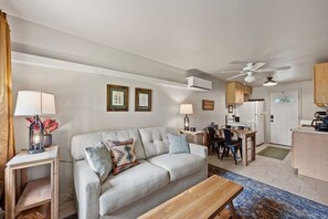 A living room with a sofa, coffee table, and a dining area with chairs and a table.