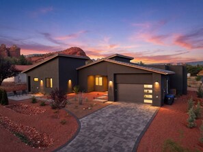 Ein modernes, zweistöckiges Haus mit Garage, Auffahrt und einem angelegten Garten.