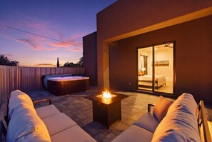 Eine moderne Außenpatio mit Feuerstelle, Whirlpool und einer Glastür zum Schlafzimmer.