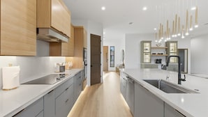 Una cocina moderna con armarios grises, electrodomésticos de acero inoxidable y una isla central con pileta.