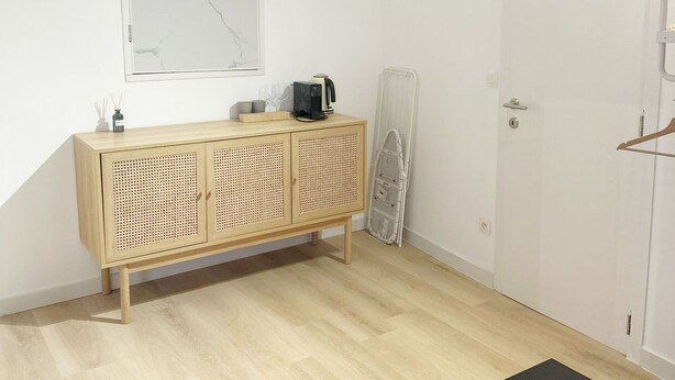 A room with a wooden cabinet, a black table with cups, a white door, and a wall-mounted mirror. - Convenient Studio in the Heart of City (Ghent)