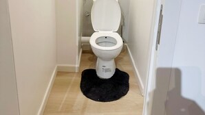 A narrow bathroom with a white toilet, a black rug, and a tiled floor. - Convenient Studio in the Heart of City (Ghent)