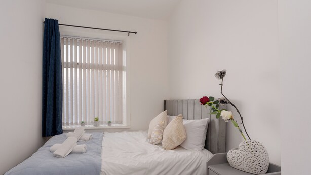 A neatly arranged bedroom with a bed, bedside table, and a window with blinds. - 4 bedroom house,  sleeps 8, fast WIFI, shops, long stays, pet friendly (Nelson)