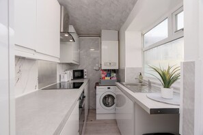 A compact kitchen with a washing machine, microwave, and sink. - 4 bedroom house,  sleeps 8, fast WIFI, shops, long stays, pet friendly (Nelson)
