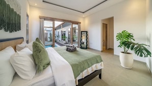 A bedroom with a bed, a large mirror, a potted plant, and a view of the outside. - La Palma Villa Bali (Kerobokan)