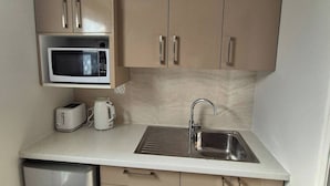 A compact kitchen with a microwave, toaster, kettle, sink, and a small refrigerator. - Apartment in the heart of Bondi (Bondi)
