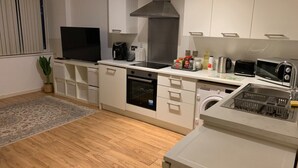 A modern kitchen with white cabinetry, a built-in oven, a microwave, a coffee maker, and a sink. - Cosy Apartment with great Wi-Fi, City Centre (Nottingham)